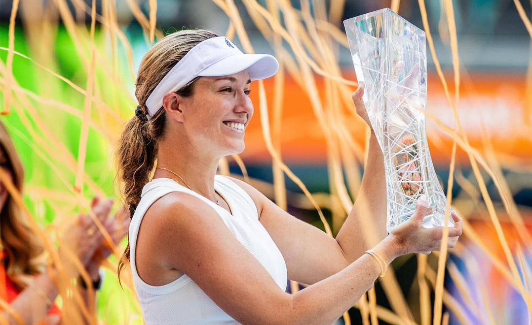 Danielle Collins holding Miami Open championship trophy with streamers in background