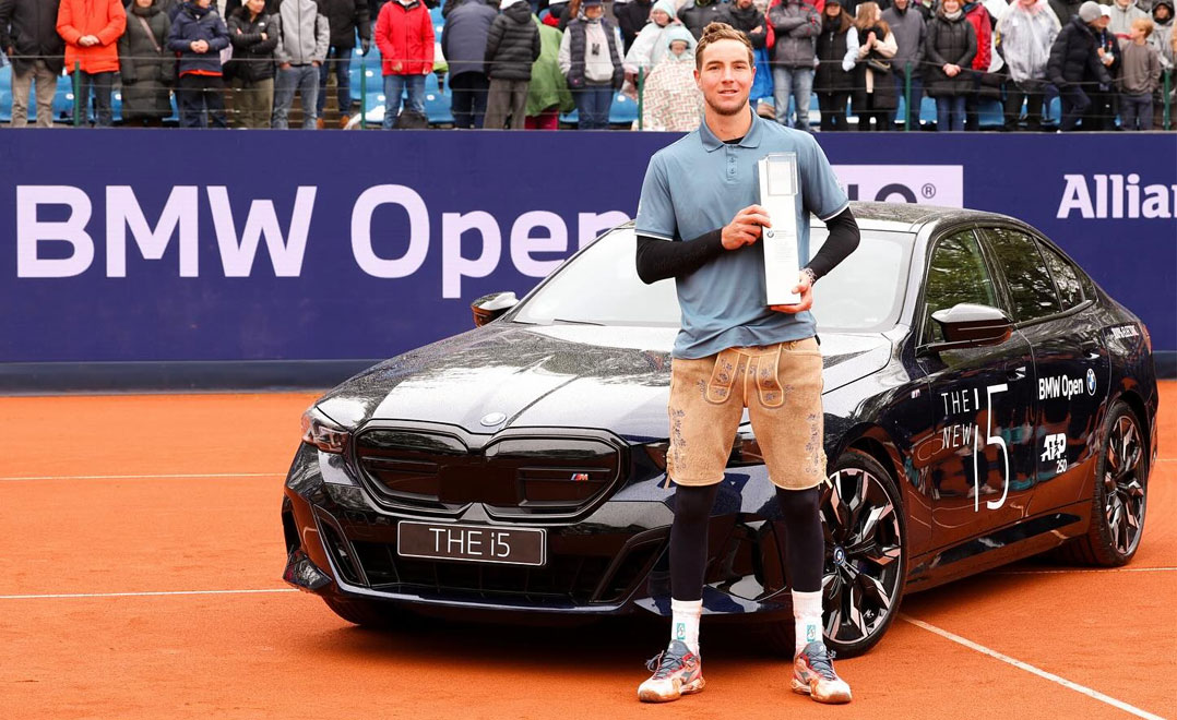 Jan-Lennard Struff holds the trophy for the 2024 BMW Open in front of a new BMW i5 M60.